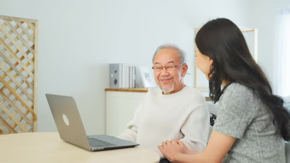 Asian senior male and daughter video call with doctor in living room. alt