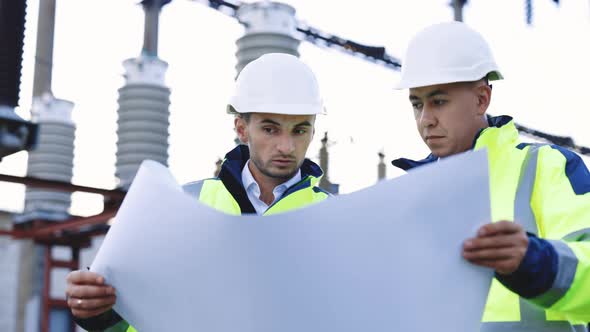 Two Engineers are Talking in Front of Electrical Transmission Lines alt