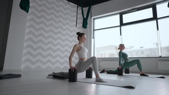 Group of Young Women Stretching in Gym with Windows alt