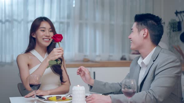 Asian young man surprise and give rose flower to beautiful girlfriend. alt