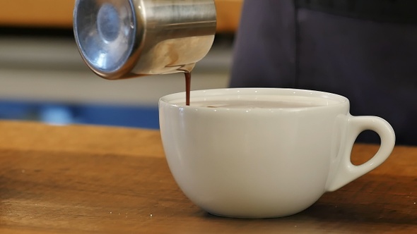 Pouring coffee into cup with milk
