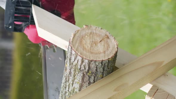 Vertical Shot Caucasian Man in Gloves Saws Firewood with Electric Saw at Home Site