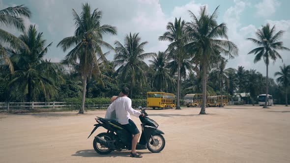 Woman Kisses Man Sitting on Motorcycle Girl Waves Hand alt