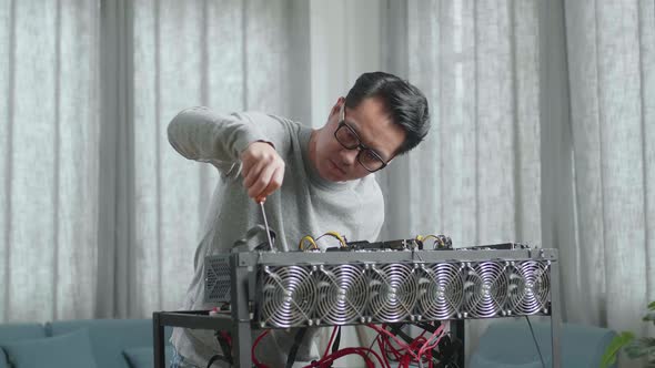 Asian Man Wearing Glasses Fixing The Mining Rig For Mining Cryptocurrency alt