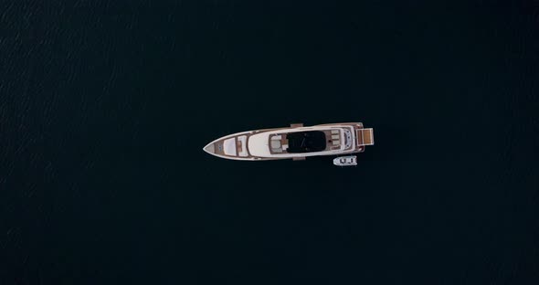 Aerial ascent over luxury yacht anchored in middle of the ocean; top-down alt