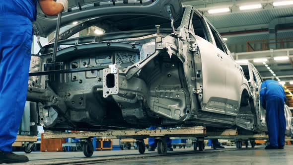 Several Workers Assembling Cars on an Assembly Line of a Car Production Factory. alt