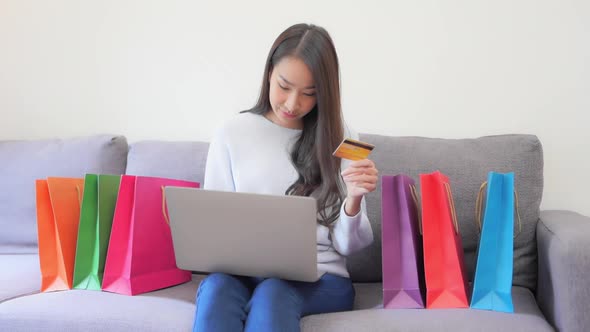 While shopping from home, a young woman holds up her credit card as she inserts the numbers into her alt