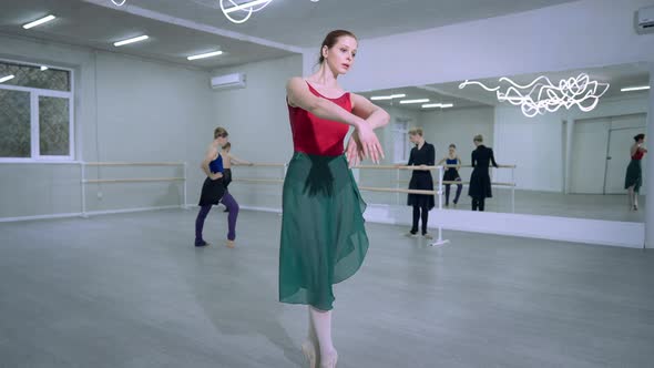 Concentrated Young Slim Ballet Dancer Rehearsing Pas and Tendu Movements in Studio with Ballerinas alt