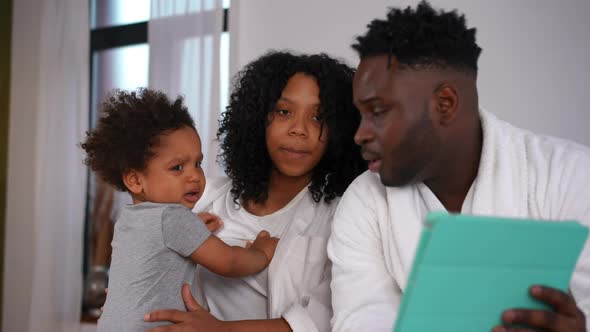 Curios Little Toddler Boy and Smiling Beautiful Woman Listening Handsome Man Talking Showing Tablet alt