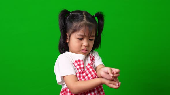 Portrait of happy and funny Asian child girl on green screen background, a child looking at camera. alt