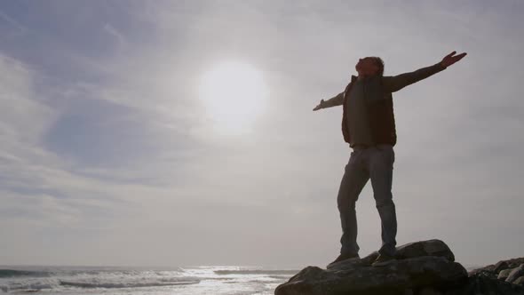 Caucasian woman enjoying free time by sea on sunny day standing with arms wide alt