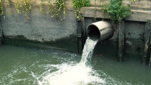 Wastewater flows down from sewer pipe and pollutes water in river at downtown alt