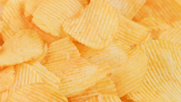 Looped Spinning Yellow Wavy Potato Chips Full Frame Closeup Background alt