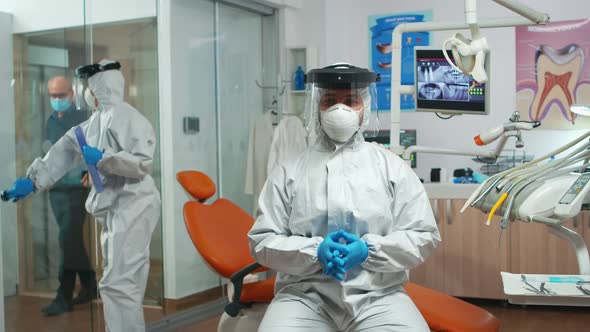 Dentist with Coverall Looking at Camera Talking with Patients alt