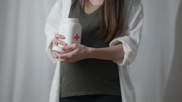 Unrecognizable Pregnant Woman Opening Pills Bottle Pouring Out Capsules on Hand alt