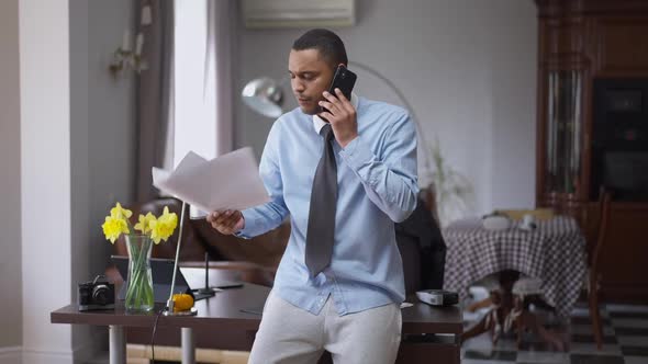 Nervous Stressed African American Man Talking on the Phone Gesturing with Graphs in Hand alt