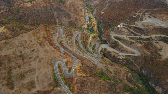 Vehicles Moving Along Winding Road Among Hills with Golden Dried Out Grass in Armenia alt
