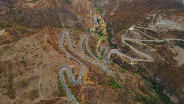Vehicles Moving Along Winding Road Among Hills with Golden Dried Out Grass in Armenia