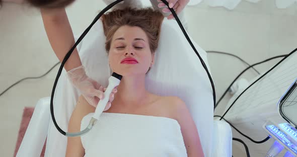Beautiful Woman at a Cosmetologist's Reception Receives a Vacuum Massage of the Skin of the Face alt