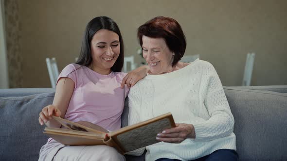 Mother and Daughter Looking at Photo Album Together alt