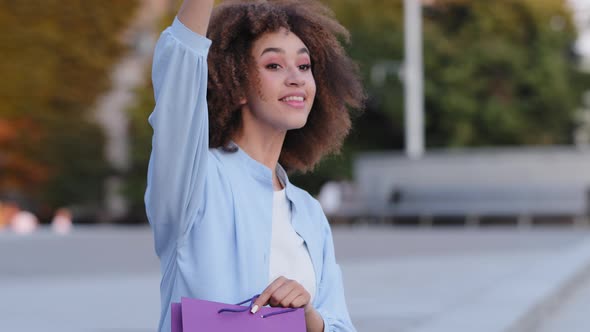 Young Active African American Girl Afro Woman Sitting Outdoors in City Peeping Someone Waving Hand alt