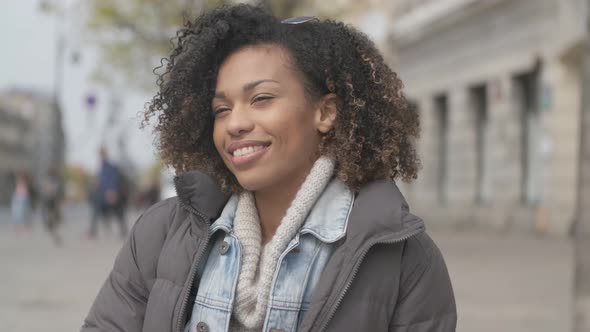 Beautiful Girl with Afro Haircut Sitting on Bench at City Street alt