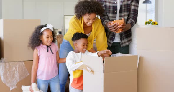 Front view of black family unpacking cardboard boxes at comfortable home 4k alt