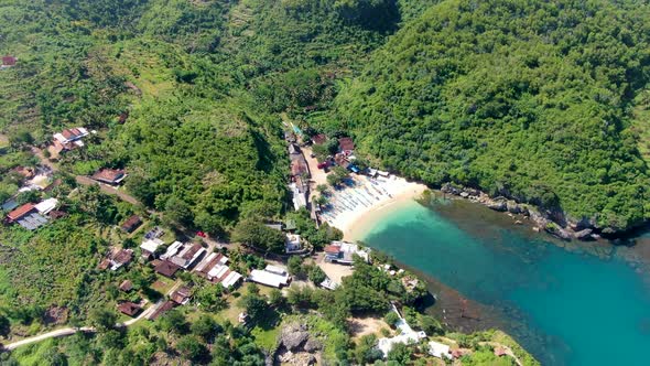 Tiny white sand Gesing beach by steep cliffs and remote village on Java coast alt