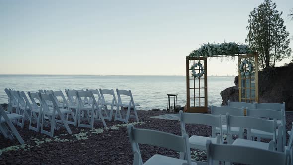 Luxury wedding ceremony location on the shoreline with white chairs alt