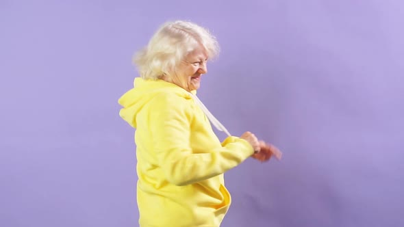 Stylish Granny in a Yellow Sports Sweatshirt Moving To Music, Dancing Party, Style alt