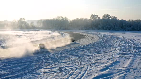 Slow Motion Aerial Shot of Two Cars Drifting on the Ice of a Frozen Lake
