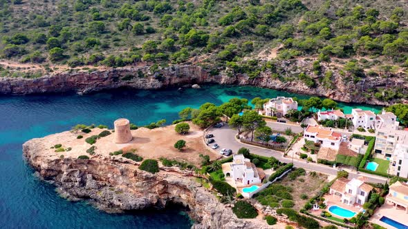 Tower of Torrent de Cala Pi on the Mallorca Spain island coast, Aerial orbit left shot alt