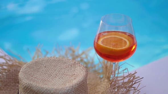 Cocktail Glass in Front of a Straw Hat Placed on a Wooden Boardwalk By the Pool