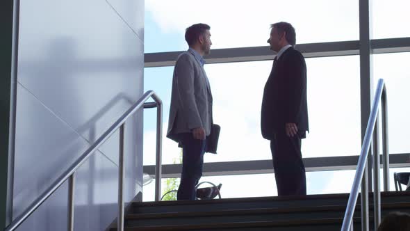 Business people meeting and shaking hands at top of stairs
