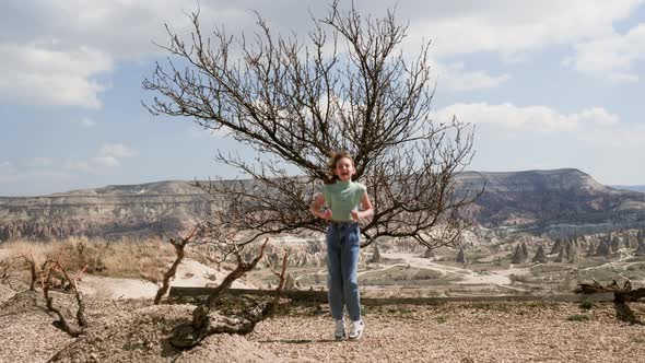 Happy Teen Girl Jumping on Highland Peak with Amazing View Cappadocia Valley alt