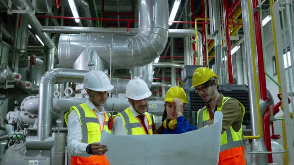 Engineerc and Foreman are discussing the plant layout on the blueprint in the factory boiler room