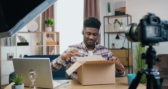 Blogger Sitting in front of Videocamera and Recording Unpacking Process alt