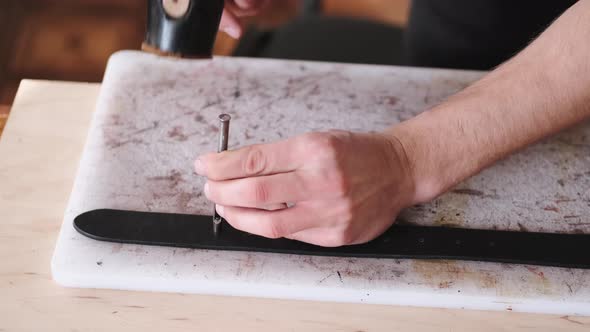 The Leather Craftsman Is Making Holes in a Hand-made Belt alt