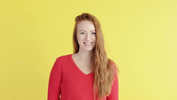 woman on yellow background looks into camera and smiles