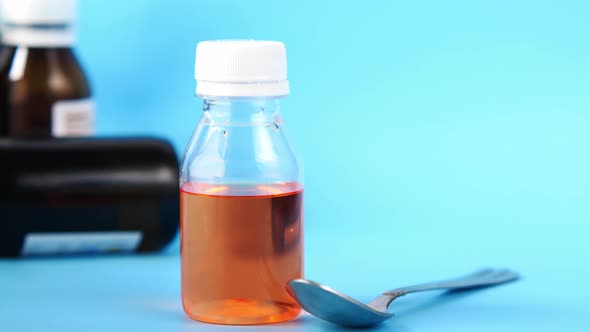 Bottle with Liquid Medicine on Blue Background alt