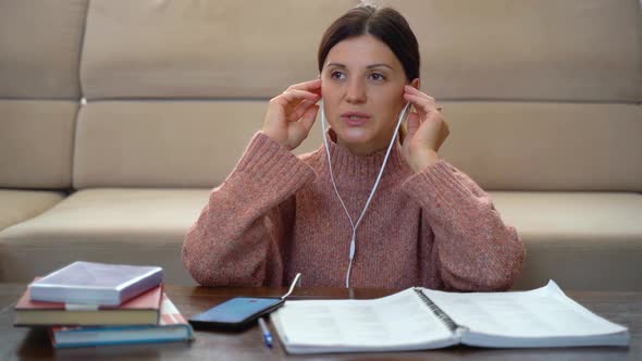 A woman in headphones learns to speak a foreign language, online lesson alt