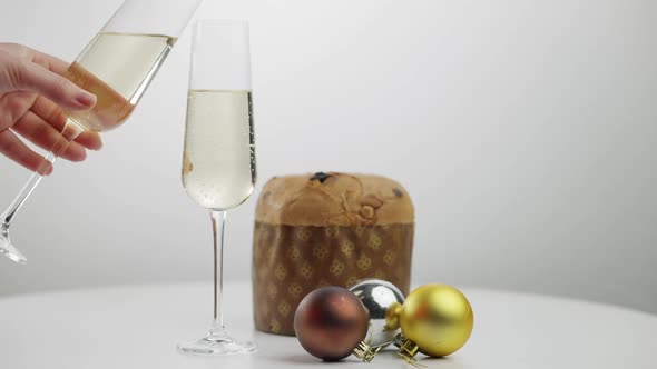 Traditional Christmas Sweet Bread and Decorations on Table with Young Female Hand Clinking Champagne alt