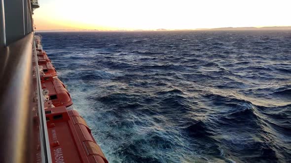 Beautiful horizon view at open sea from a cruiser navigating on sunset hour. Sea is agitated. Waves alt
