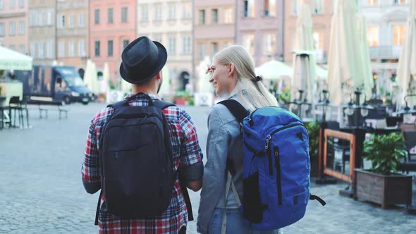View of Tourists Couple with Bags Checking Map on Central City Square alt