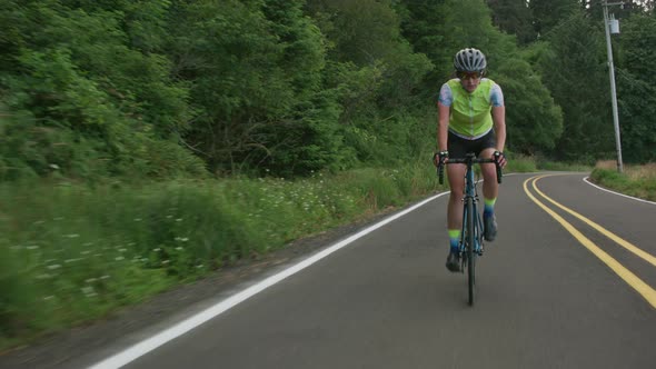 Tracking shot of a female cyclist on country road.  Fully released for commercial use.