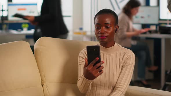 African Manager Discussing with Remote Colleagues on Video Call Holding Smartphone alt