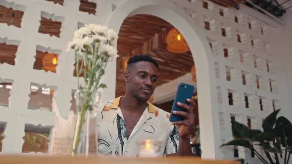 Young AfricanAmerican Man Uses Smartphone Outdoors alt