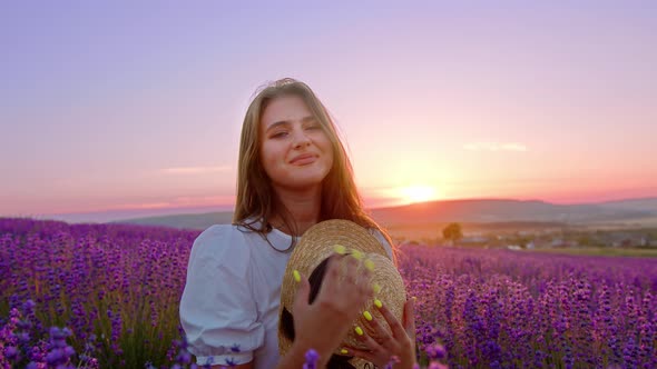 Beautiful Young Woman Wearing White Dress and Hat Standing in a Lavender Field