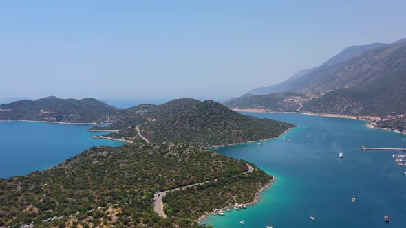 Aerial drone panning left across a peninsula full of large green hills in Kas Turkey and anchored bo alt