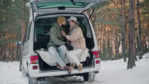 Romantic Couple Sitting at the Back of Van in the Woods on a Sunny Winter Day